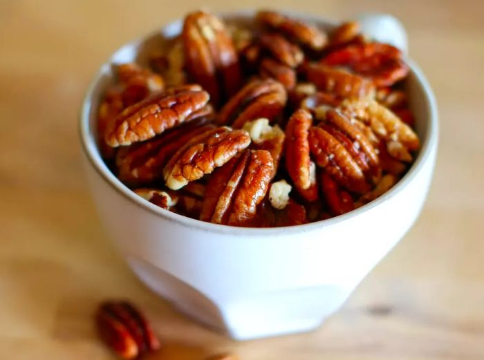 A plate of toasted pecans on a cutting board