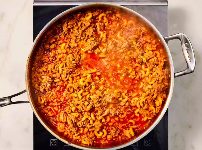 Pasta and sauce simmering together in a pan during the preparation of Pasta e Fagioli.