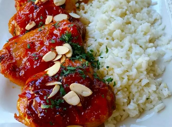 Apricot glazed chicken thighs served with rice on a white plate