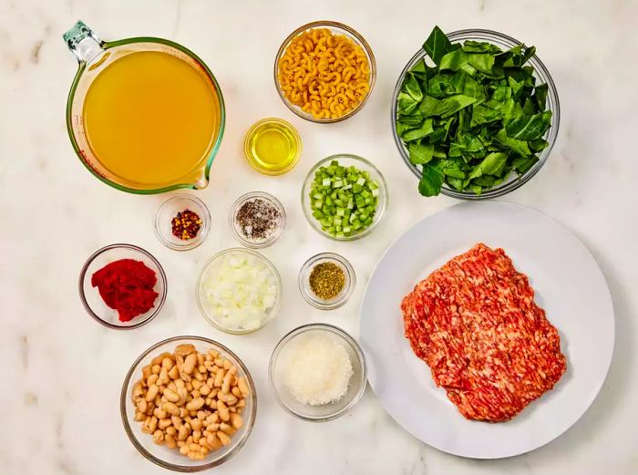 Ingredients for Pasta e Fagioli neatly arranged in small bowls on the kitchen counter.