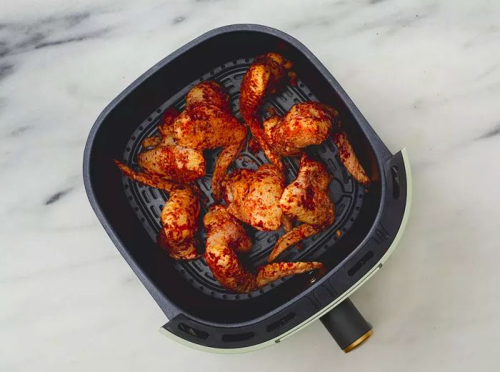 Chicken wings placed in the air fryer basket.