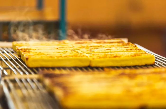 Freshly baked bread cheese with steam rising from its surface.