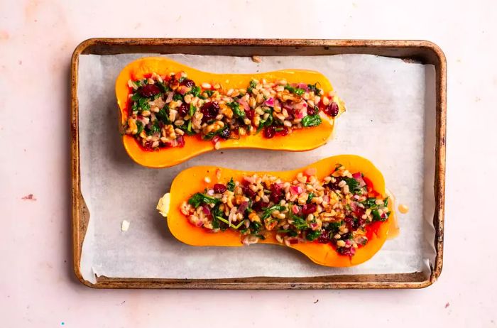 Stuffed butternut squash, baked and placed on a parchment-lined baking sheet.