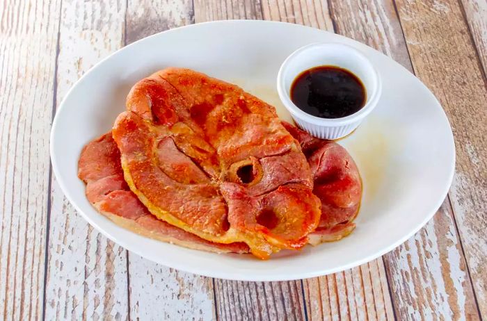 Country ham slices served with red eye gravy on a white plate