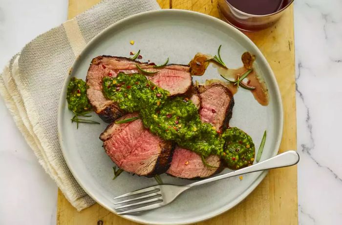 A plated serving of medium-rare Santa Maria tri-tip topped with chimichurri sauce