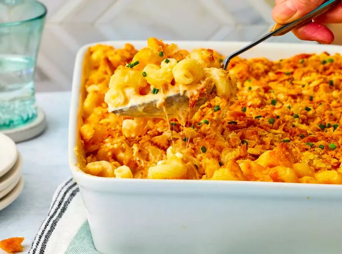 A spoonful of rich, creamy 'million-dollar' mac and cheese being scooped from a baking dish.