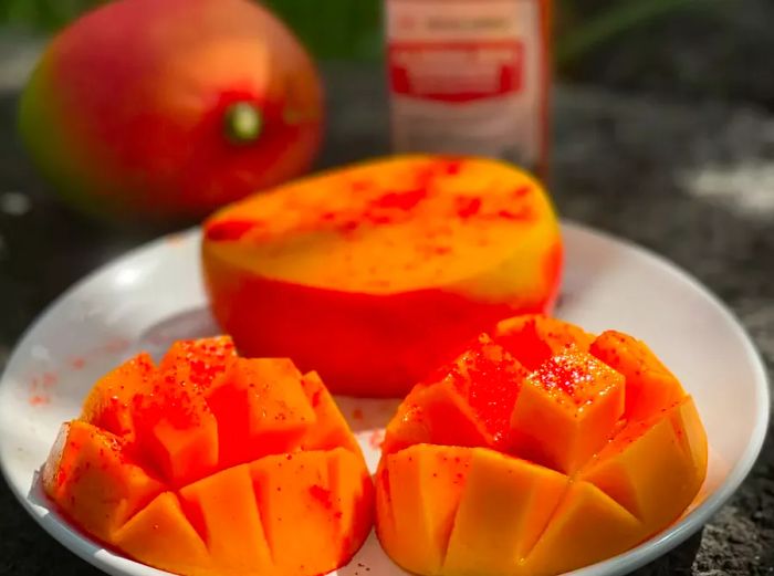 A close-up of a mango sliced and dusted with bright red li hing mui powder.