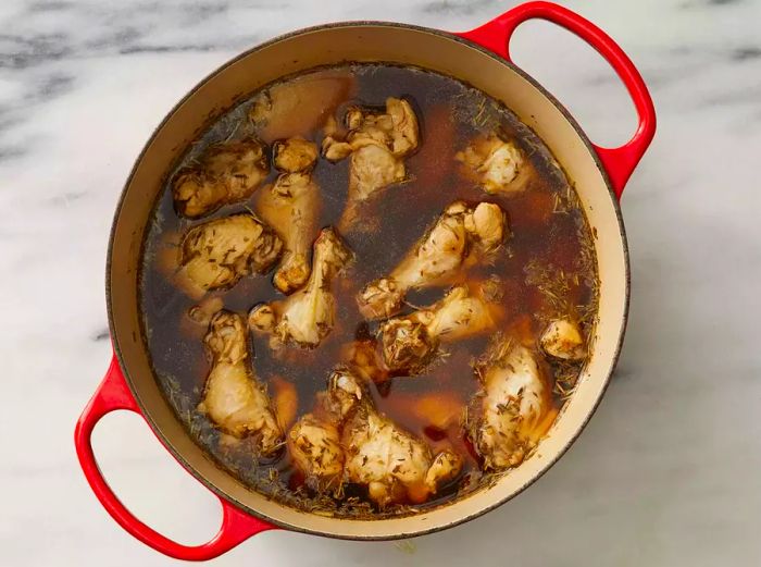 A Dutch oven filled with chicken wings soaking in flavorful broth.