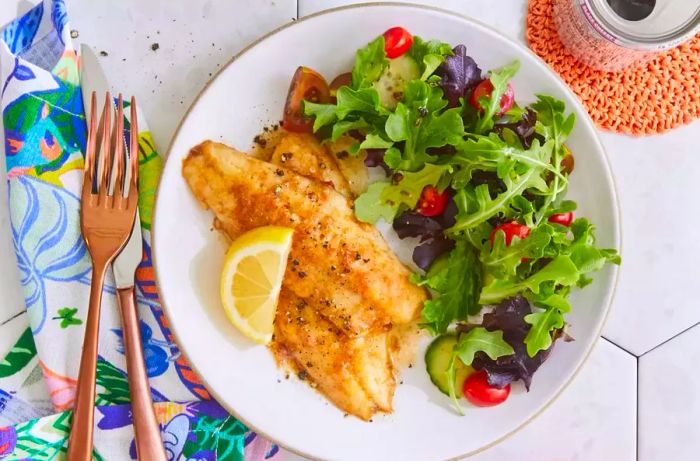 A top-down view of brown butter perch, served alongside a fresh green salad.