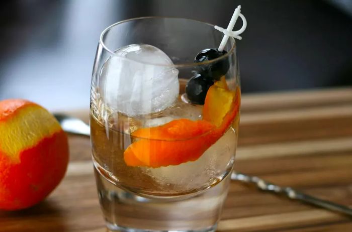 A portrait shot of a mezcal old fashioned, garnished with a floating slice of orange peel