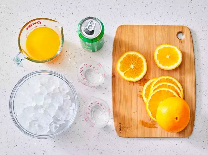 Ingredients for making a fresh Orange Crush cocktail with squeezed orange juice and vodka