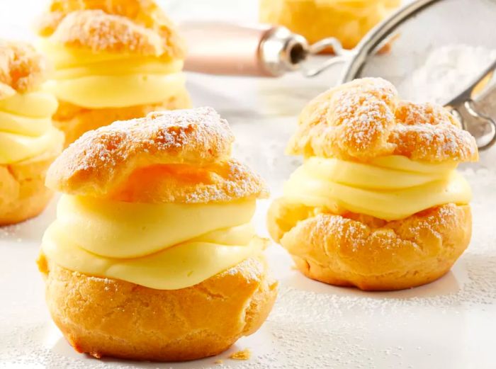 Low-angle view of a plate of cream puffs dusted with powdered sugar.