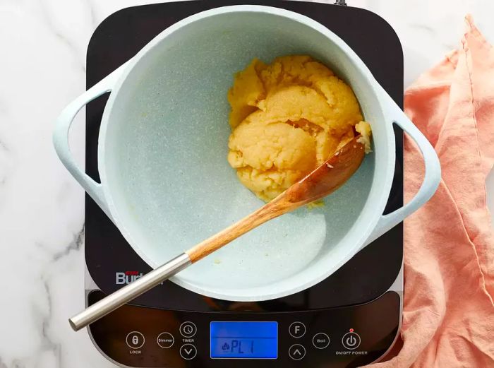 Aerial view of a flour and salt mixture formed into a dough ball in a pot.