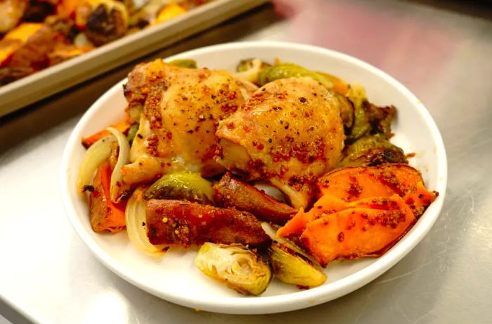 Sheet pan chicken and veggies with mustard vinaigrette served with Brussels sprouts, onions, and sweet potatoes