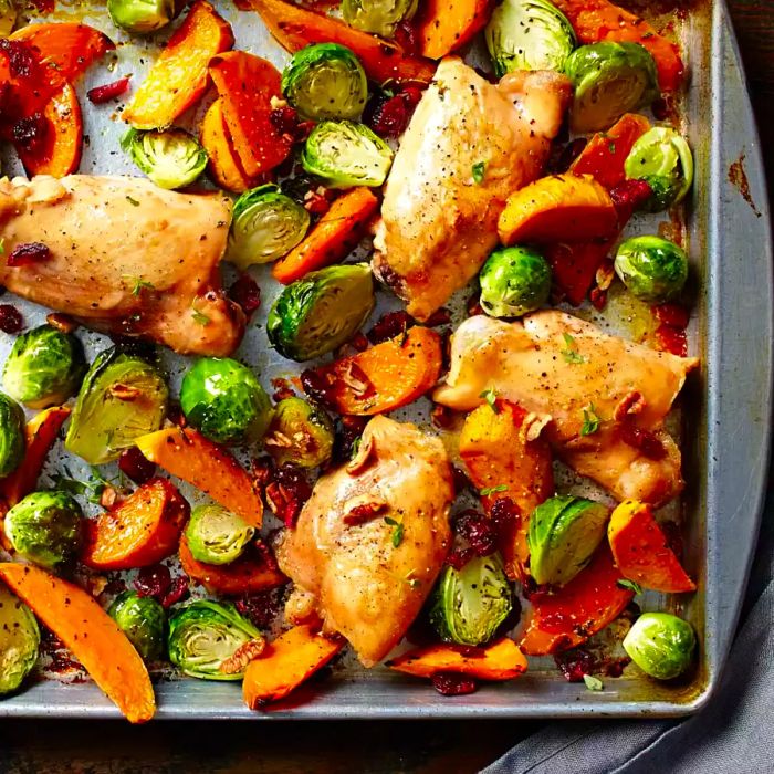 A sheet pan featuring chicken thighs, Brussels sprouts, and sweet potatoes, all roasted to perfection