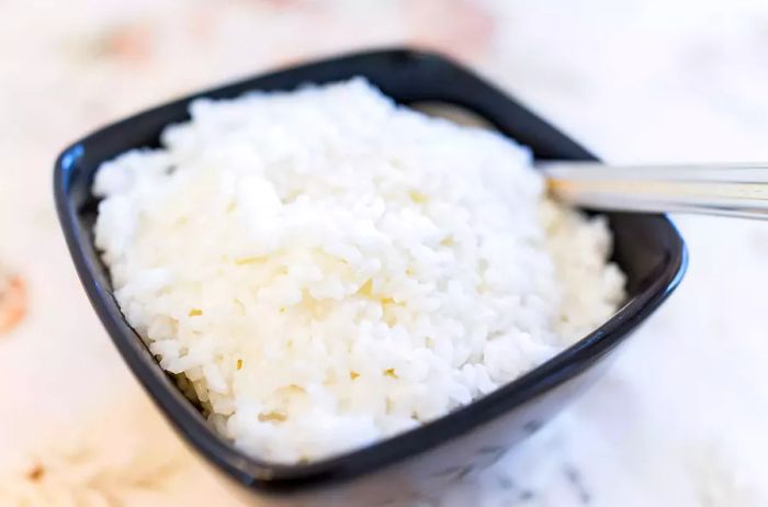 A bowl of white jasmine rice with a fork in it