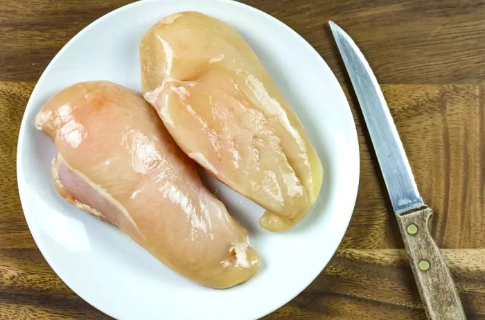 Raw chicken breast on a white plate
