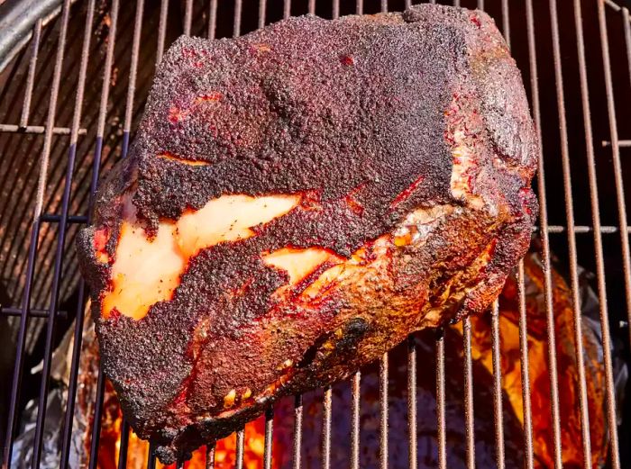 A brined and spice-rubbed pork shoulder slowly smoking in the smoker