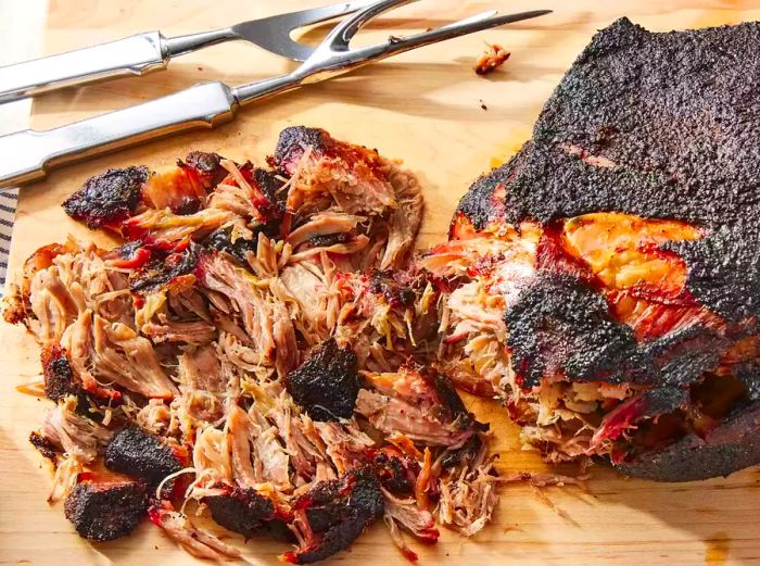 A cutting board with tender, shredded pulled pork ready to serve