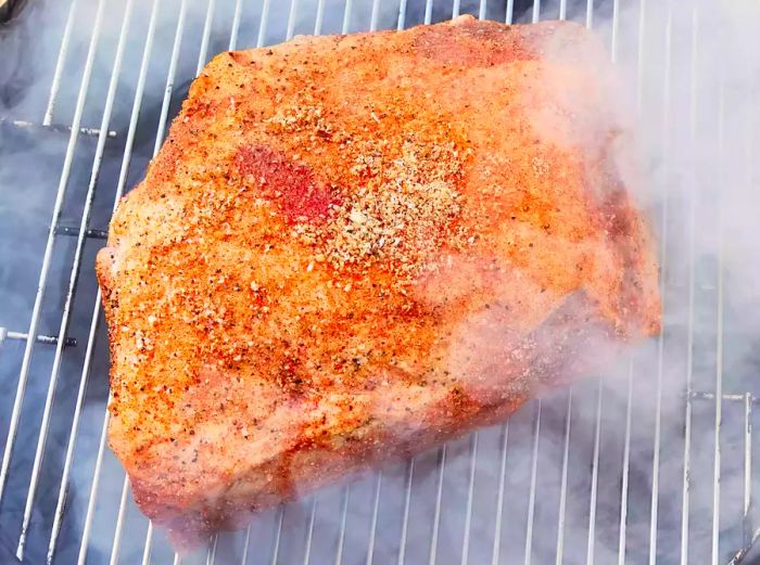A brined and spice-coated pork shoulder inside the smoker