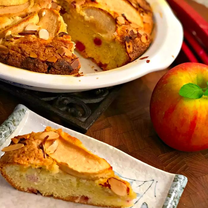 A slice of French-style apple rhubarb cake, topped with slivered almonds, ready to enjoy.