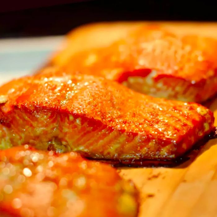 Three center-cut salmon fillets on a cedar wood plank ready for grilling