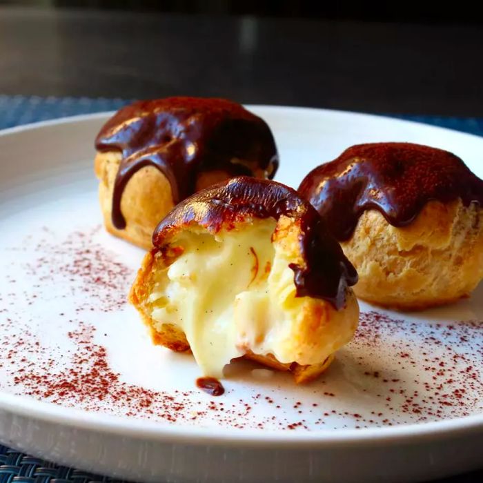 Profiteroles filled with creamy crème pâtissière, topped with a rich ganache.