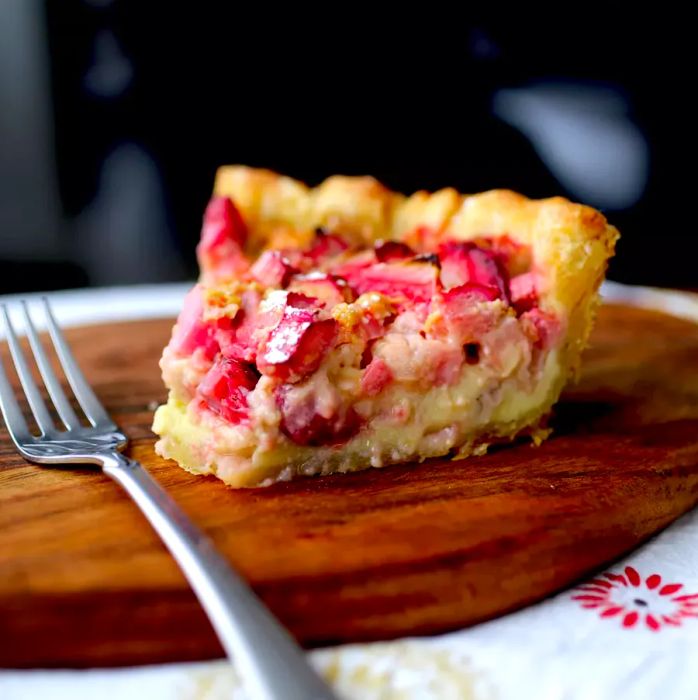 A slice of rhubarb pie resting on a rustic wooden board