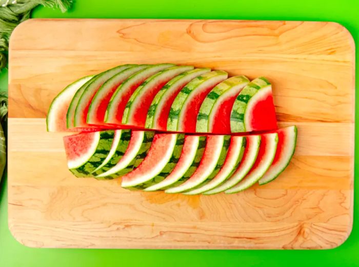 A bird's eye view of watermelon wedges arranged neatly on a cutting board.