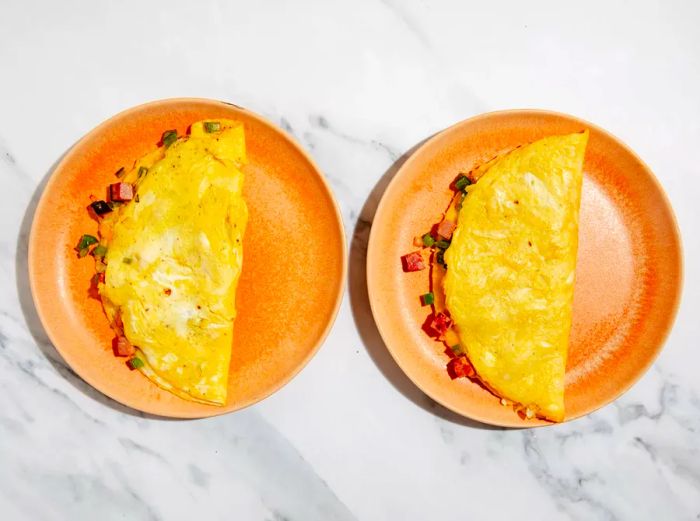 Top-down view of two omelets served on plates side by side