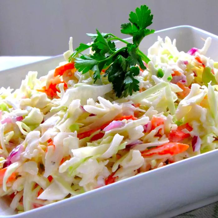 A white bowl filled with creamy coleslaw made from shredded carrots and green cabbage