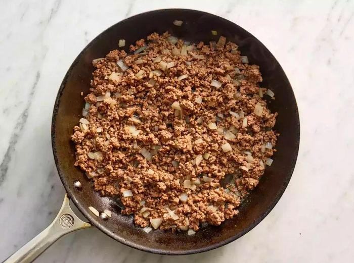 Ground beef and onions sizzling in a skillet