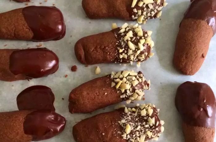 An overhead shot of Chocolate Chip Shortbread Cookie Logs, dipped in smooth melted chocolate and topped with crushed nuts for a crunchy finish.