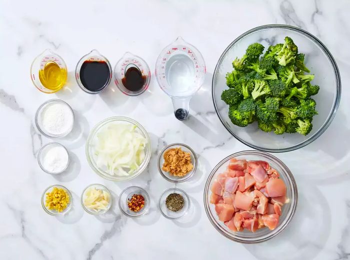 All the ingredients for the broccoli chicken stir-fry neatly arranged in glass bowls on the kitchen counter.