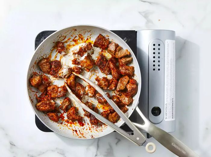 Beef browned and seasoned with flour added to the skillet