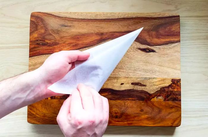 Shaping a parchment paper triangle into a piping cone