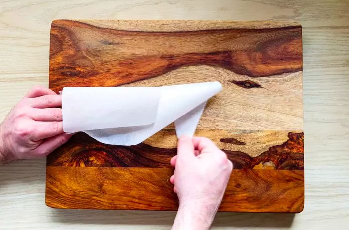 Folding a parchment paper triangle to form a piping cone