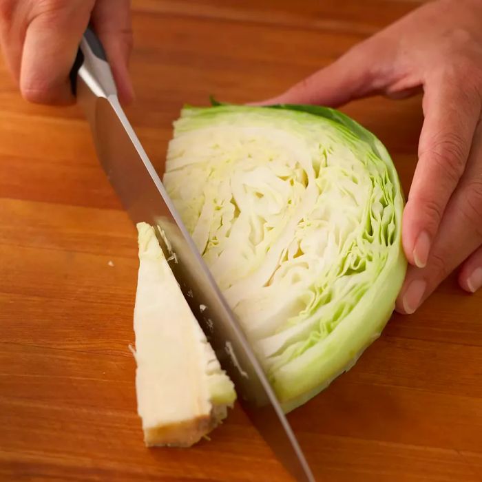 A person cutting out the core from a cabbage slice