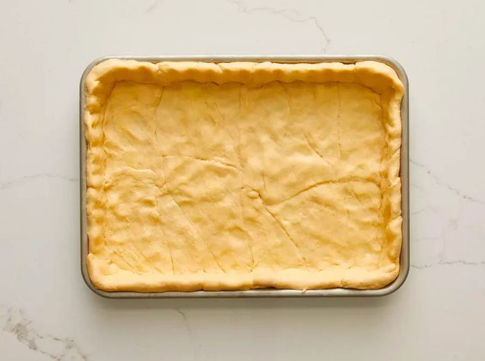 Aerial view of crescent dough pressed into a pan, ready for pizza baking