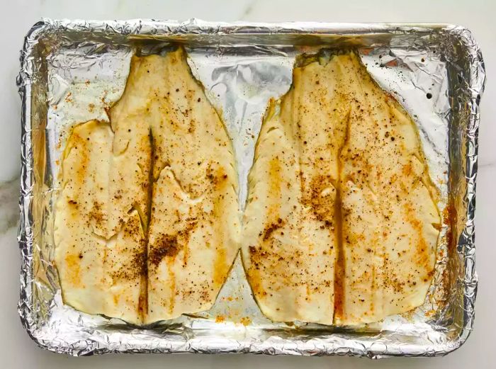 Broiled trout resting on a foil-lined baking sheet