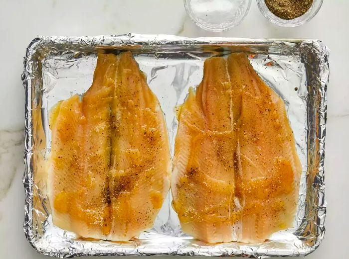 Raw trout placed on a foil-lined baking sheet