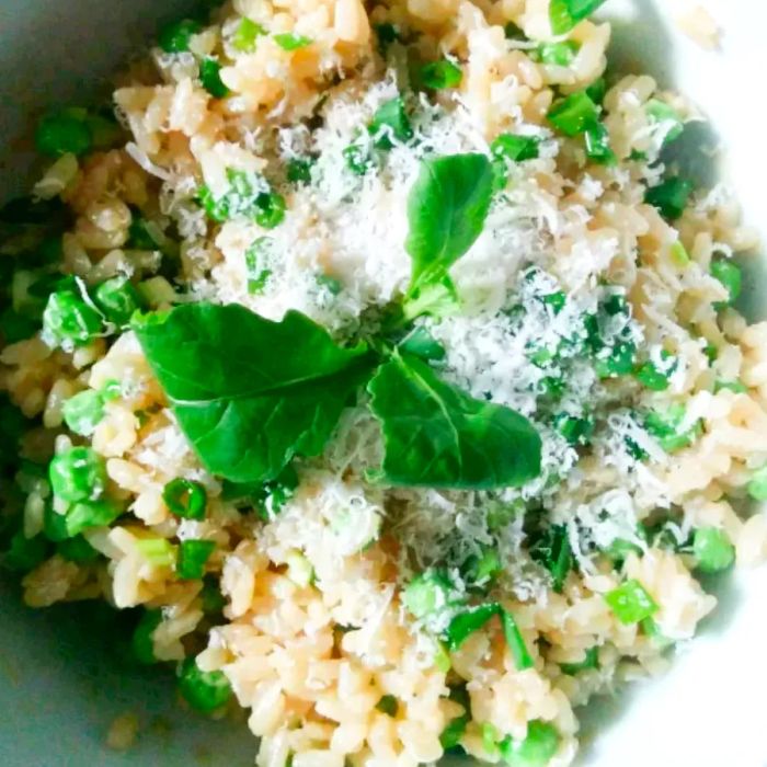 close-up image of risotto with peas, topped with fresh herbs and cheese, served in a bowl