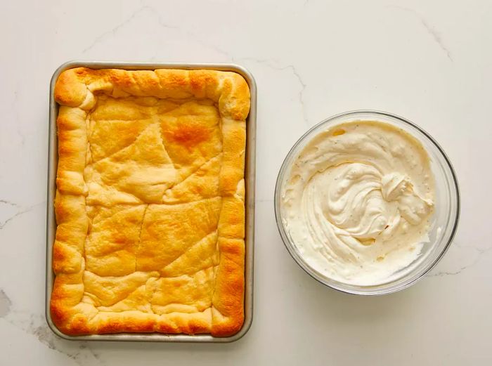 Aerial view of baked crescent dough next to a bowl filled with the creamy mayo-cream cheese mixture