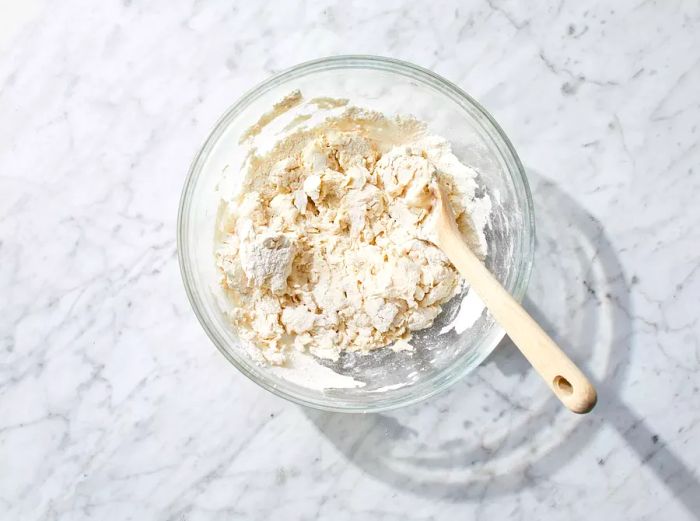 Dough ingredients combined in a bowl until the mixture starts to come together.