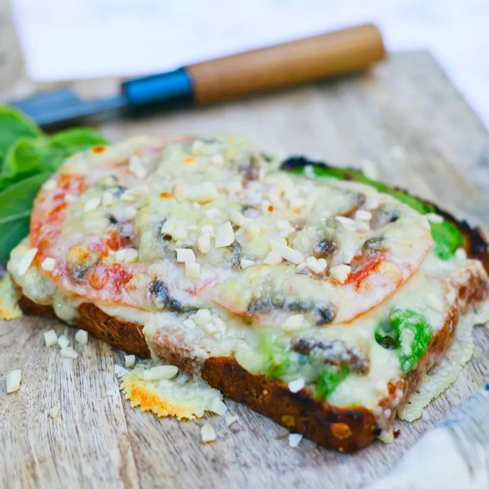 A close-up shot of a California melt – fresh veggies atop a piece of bread, all covered in gooey melted cheese.