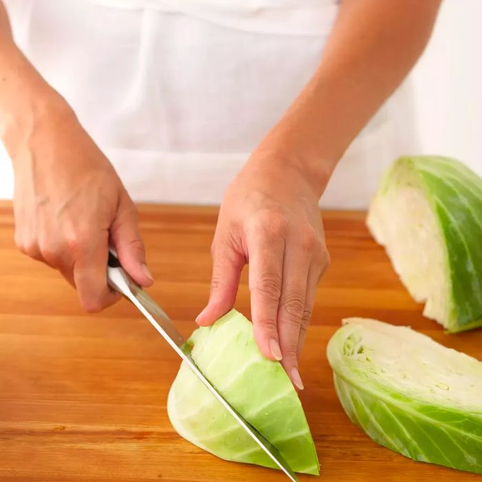 A person slicing cabbage wedges with a chef's knife