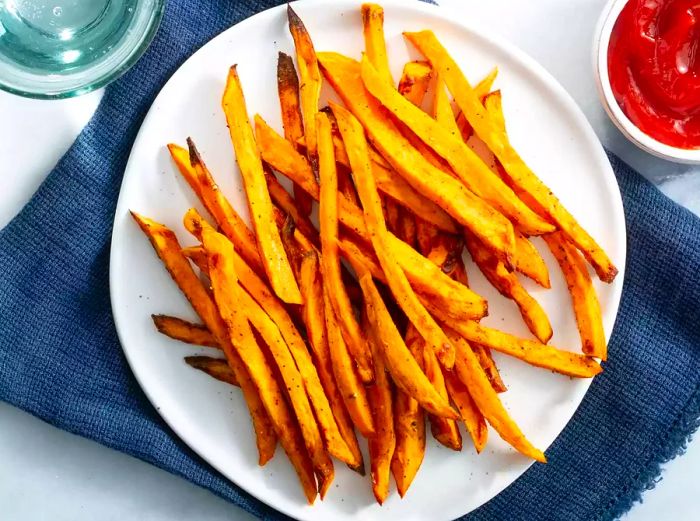 An overhead view of air-fried sweet potato fries paired with a side of ketchup.