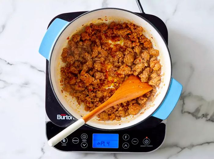 A large pot filled with browned ground sausage