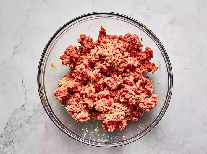 Aerial shot of ground meat in a mixing bowl, ready to be formed into meatballs