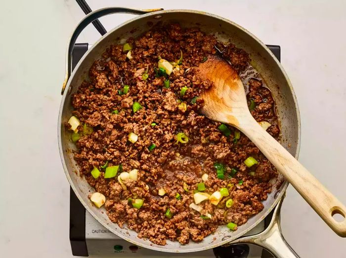 A pan of seasoned ground beef topped with sliced green onions